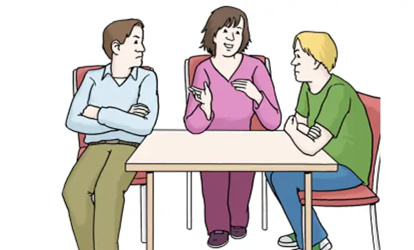 Drei Personen sitzen an einem Tisch und unterhalten sich