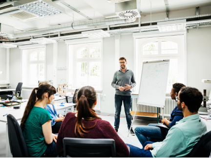 Ein Lehrer spricht vor einer Gruppe Studierender